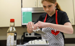Person preparing sushi rolls on a plate in a kitchen with a bottle of soy sauce nearby. Person preparing sushi rolls on a plate in a kitchen with a bottle of soy sauce nearby.
