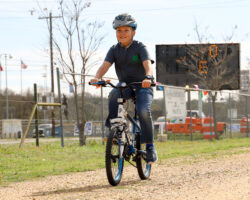 Person riding a bicycle on a gravel path at an outdoor event. Person riding a bicycle on a gravel path at an outdoor event.