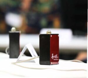 Close-up of a Zeecraft quiz bowl buzzer on a table with a connected cable and another buzzer in the background.