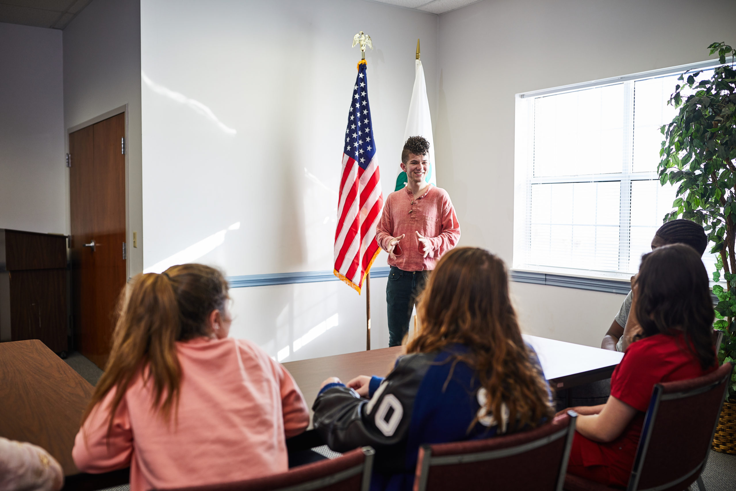 Texas 4-H member presenting during a leadership session with U.S. and 4-H flags displayed. Texas 4-H member presenting during a leadership session with U.S. and 4-H flags displayed.