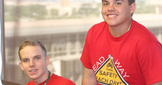 Two individuals wearing red shirts with a printed safety message promoting daily awareness.