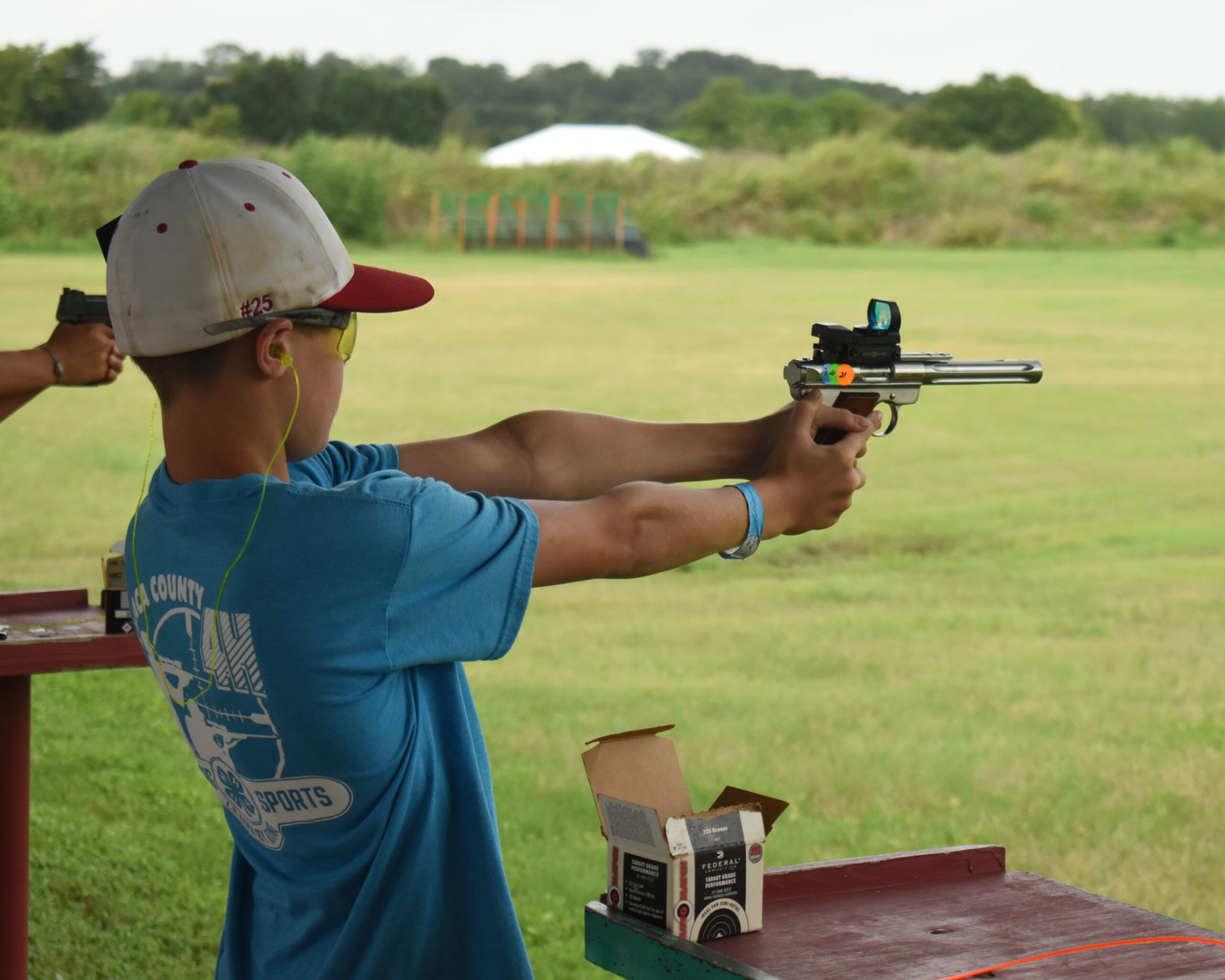 Target shooting practice with a pistol at a range. Individual aiming a pistol at an outdoor shooting range with ear and eye protection.